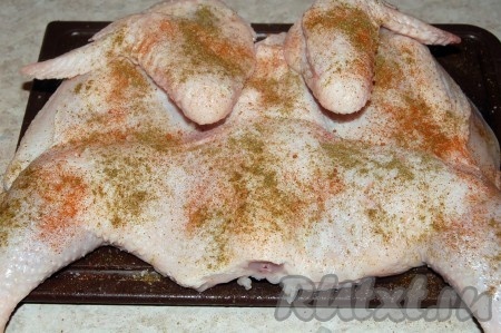 Вытащить цыплёнка из воды, обтереть салфеткой и обсыпать специями с двух сторон.