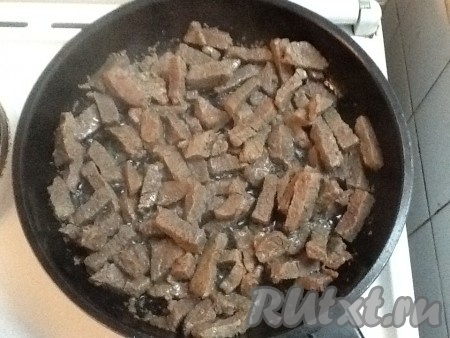 В сковородку к мясу, из которого уже выпарилась вода, добавить лук. Если нужно, подлить немного растительного масла.