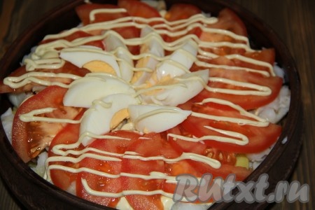 Поверх рыбы выложить кружочки (или ломтики) помидора. В середину выложить дольки яйца. Сделать сеточку из майонеза. 