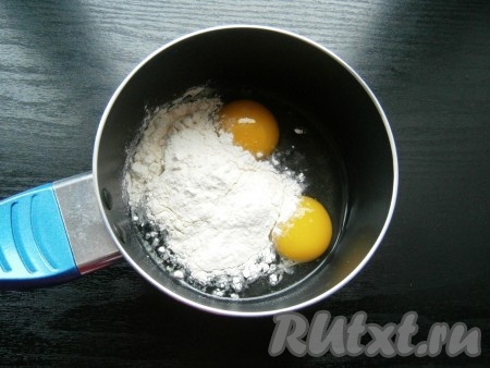 Для приготовления крема в ковшик разбить 2 яйца, добавить муку.

