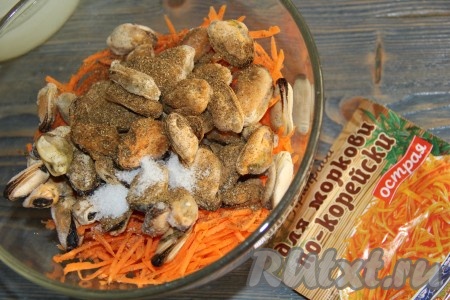 Затем к моркови выложить мидии, предварительно не размораживая их, посолить и добавить приправу для моркови по-корейски.