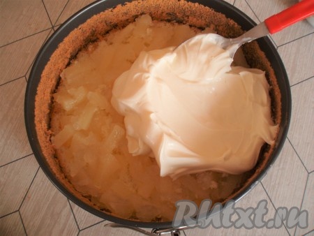 Поместить первый корж в разъемную форму, выложить половину ананасовой начинки и слой крема.

