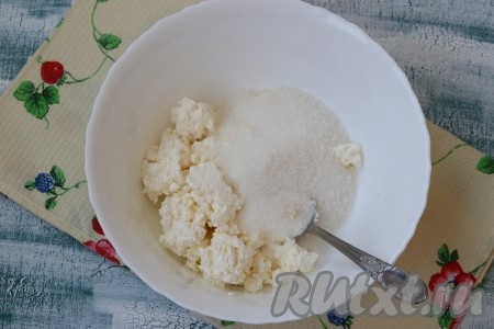 В миску выложить творог, добавить к нему ванильный сахар и сахар.
