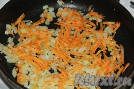 Когда лук станет золотистого цвета, выложить к нему очищенную и натертую на крупной тёрке морковь. Обжарить овощи на среднем огне в течение 5 минут, периодически помешивая.

