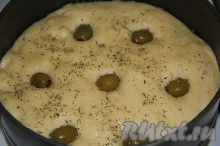 Затем выложить на тесто оливки и слегка их углубить в тесто. Присыпать тесто душистыми травами. 
