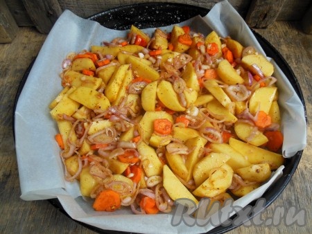 На противень, застеленный пергаментом, выложите картошку, перемешанную с луком и морковью, и отправьте в разогретую духовку.
