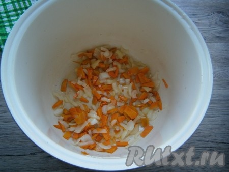 В чашу мультиварки налить растительное масло и на 15 минут выставить режим "Выпечка". Добавить в чашу нарезанные небольшими кусочками лук и морковь. Обжарить овощи, помешивая, до сигнала.
