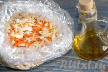 Выложить капусту, морковку и лук в рукав для запекания. Влить масло в пакет, добавить лавровые листья.
