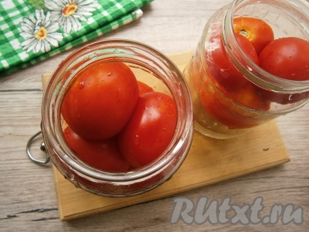 В чистые баночки уложить твердые помидоры.
