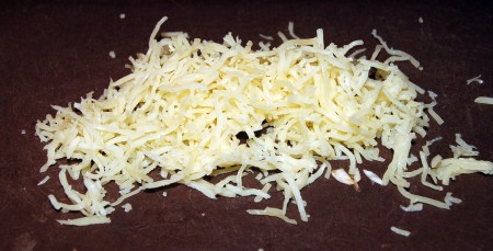Теперь натираем сыр на мелкой тёрке, посыпаем конгрио с овощами сверху сыром и отправляем запекаться в разогретую духовку минут на 20 при температуре 200 градусов.
