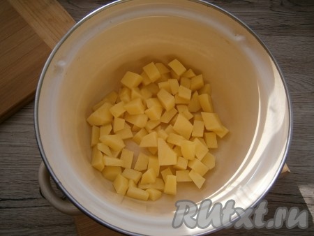 Картофель очистить и нарезать небольшими кубиками в кастрюлю.