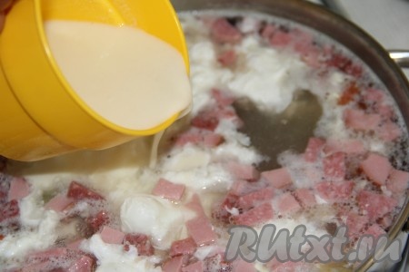 Тонкой струйкой влить мучную массу в суп с колбасой и яйцами, аккуратно и непрерывно перемешивая.
