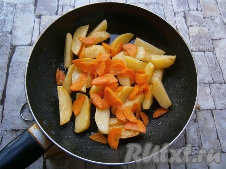 Влить в сковороду растительное масло, разогреть. Выложить в масло картофель, обжарить его на среднем огне, перемешивая, до легкой румяности. Затем добавить нарезанную полукружочками морковь, обжаривать все вместе минуты 4.
