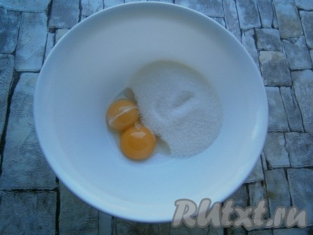 В миску разбить одно яйцо и добавить сырой желток. Всыпать сахар и щепотку соли.
