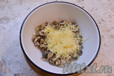 Переложить грибы в миску и сразу же, пока шампиньоны горячие, добавить натертый на средней терке твердый сыр, перемешать. Сыр должен расплавиться и "окутать" собой грибочки.
