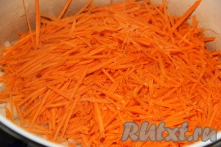 Морковь, натерев на тёрке для моркови по-корейски, выложить в кастрюлю с луком. 