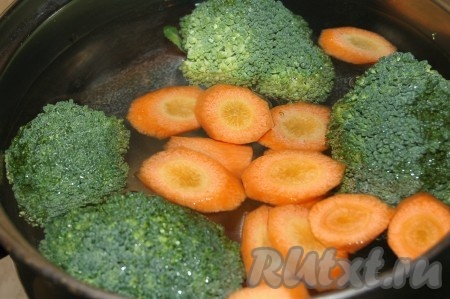 Взять небольшую кастрюльку, налить в нее воду, довести до кипения и опустить в кипящую воду соцветия брокколи и нарезанную морковь.
