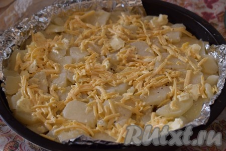 Заливаем оставшейся заливкой, равномерно распределяя сыр по всей поверхности картофельно-мясной запеканки.
