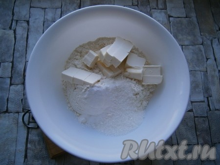 Для приготовления теста в муку добавить кусочки немного размягченного сливочного масла (или маргарина), всыпать сахар и соду.
