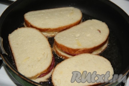 В сковороду добавить немного растительного масла и поставить на огонь. Выложить гренки с сыром и колбасой в сковороду.

