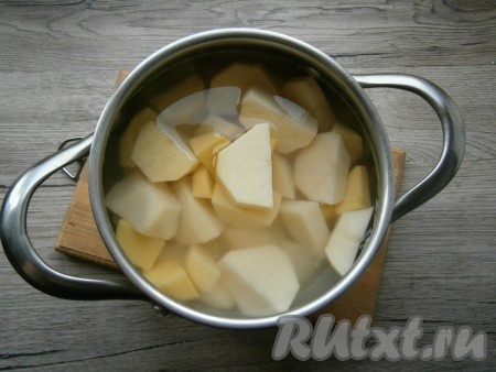 Очищенный картофель, нарезав на части, выложить в кастрюлю, залить полностью холодной водой.