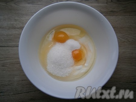 Для приготовления начинки в сметану всыпать сахар, ванильный сахар и добавить яйца.

