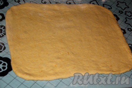 Готовое тыквенное тесто, замешанное в хлебопечке или вручную, хорошо обмять и на столе (или на силиконовом коврике), присыпанном мукой, раскатать в прямоугольный пласт толщиной 0,5-1 см.
