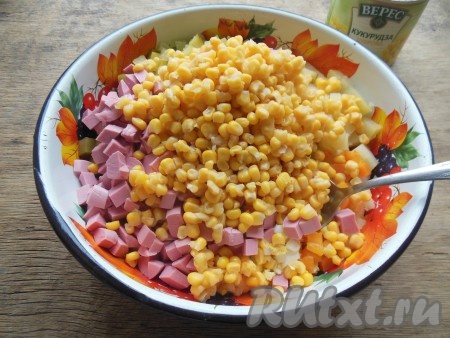 Нарезанные яйца, картошку, морковь, огурцы и колбасу сложите в глубокую миску, добавьте консервированную кукурузу без жидкости. 