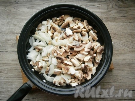Шампиньоны нарезать небольшими кусочками, также нарезать и очищенный лук. Поместить грибы с луком в сковороду, влить растительное масло.

