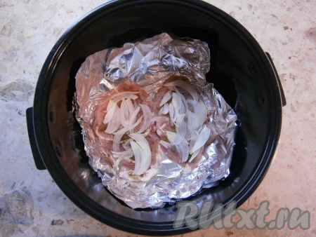 Чашу мультиварки застелить фольгой, смазать растительным маслом, выложить отбитое мясо. Сверху разместить очищенный и нарезанный тонкими полукольцами лук.
