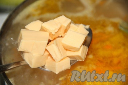 Нарезать плавленный сыр на кубики и выложить в суп с курицей.
