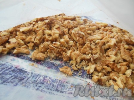 Грецкие орехи сложите в плотный пакет, завяжите его и слегка прокатайте скалкой (но не стоит измельчать орехи до состояния "пыли").

