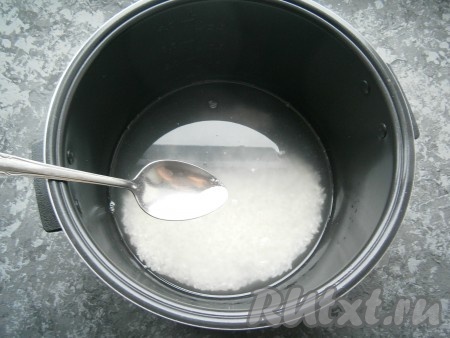 Поместить рис в чашу мультиварки, залить обычной холодной водой, всыпать соль.