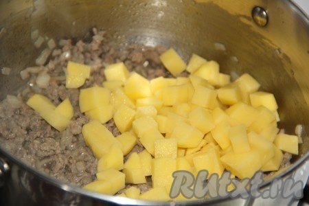 Картофель очистить, нарезать на кубики, добавить в кастрюлю с обжаренным фаршем.

