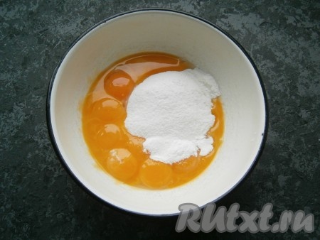 Для приготовления крема 10 сырых желтков поместить в глубокую миску, всыпать сахарную пудру.
