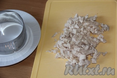 Кольцо для формирования салата поставить на плоскую тарелку. Куриную грудку заранее сварить (в течение минут 30-35) в подсоленной воде, остудить, нарезать на кусочки (или порвать на волокна).

