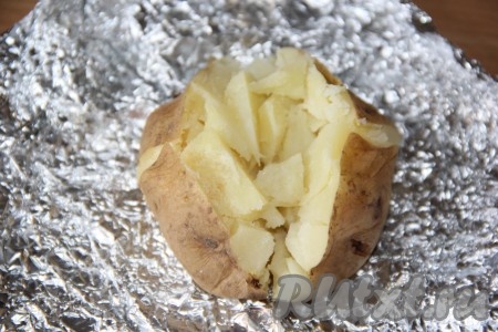 Готовый картофель вынуть из фольги. Сделать на поверхности каждой картофелины глубокий крестообразный разрез и нажать на донышко картошины. Тем самым картофель разрыхлится прямо в кожуре (как на фото).
