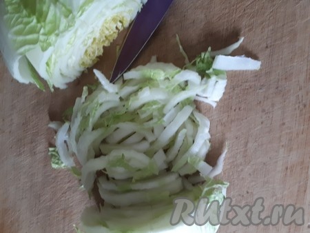 Пекинскую капусту нарезать тонкими полосками. Для приготовления этого салата желательно использовать нижнюю часть кочана - она более сочная и хрустящая. Выложить нарезанную капусту в миску.
