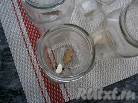 В каждую чистую сухую простерилизованную баночку поместить 1 зубчик чеснока, 1 лавровый листочек, 3 горошины чёрного перца.
