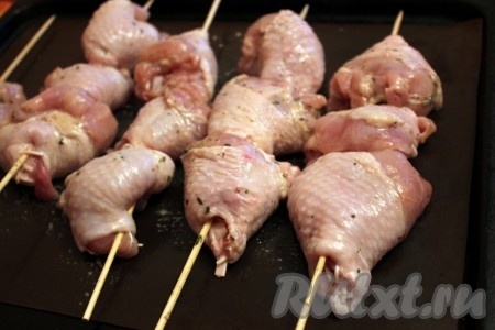 Затем нанизать куриное мясо на деревянные шпажки. Положить шашлычки из курицы на смазанный противень.