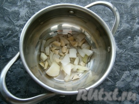 Налить оливковое масло в кастрюлю с толстым дном, добавить очищенные и произвольно нарезанные репчатый лук и чеснок.
