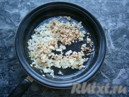 Обжарить лук с чесноком в течение 2-3 минут на среднем огне, помешивая, затем добавить в сковороду грецкие орехи.
