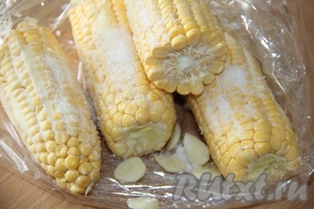 Чеснок очистить, нарезать на тонкие пластинки и выложить к кукурузе в рукав для запекания. Посыпать кукурузу солью. 
