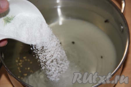 По истечении 20 минут воду из банок с огурцами вылить в кастрюлю, затем всыпать соль и сахар, поставить на огонь.
