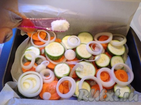 Лук, разделив на колечки, и чеснок выложить поверх моркови и кабачков. Посолить овощи, поперчить и посыпать приправой.