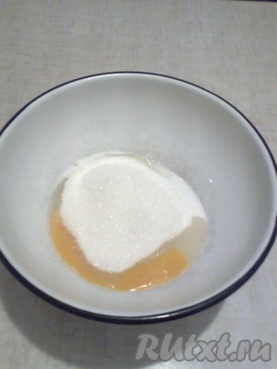 В миску вбиваем куриное яйцо, добавляем сахар и щепотку соли.
