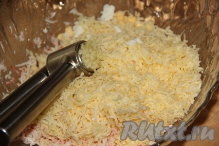К желткам и крабовым палочкам добавить чеснок, пропущенный через пресс, и натёртый на мелкой тёрке сыр.
