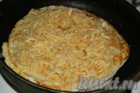 Посыпать сверху натёртым сыром. Накрыть сковороду крышкой и готовить яичницу в лаваше 5 минут на медленном огне.
