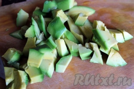 Авокадо разрезать ножом на две половинки, вынуть косточку, очистить от кожуры и нарезать кубиками.
