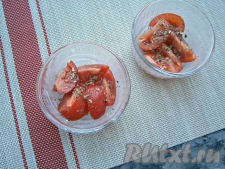 Кокотницы смазать сливочным маслом, выложить помидоры черри, разрезанные на 2-4 части (обычный помидор нарезать на средние дольки), посыпать немного чёрным молотым перцем, солью и сушёным орегано.
